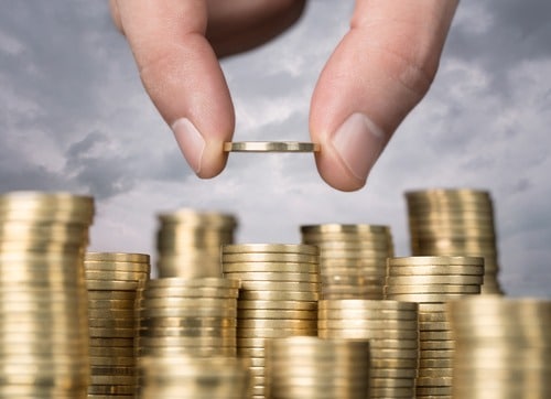 Savings, close up of male hand stacking golden coins over sky ba